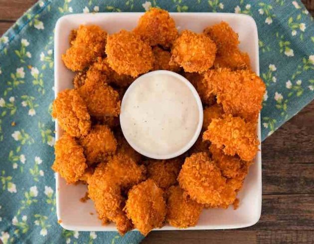 Dorito chicken bites on a serving plate with a ranch dipping sauce
