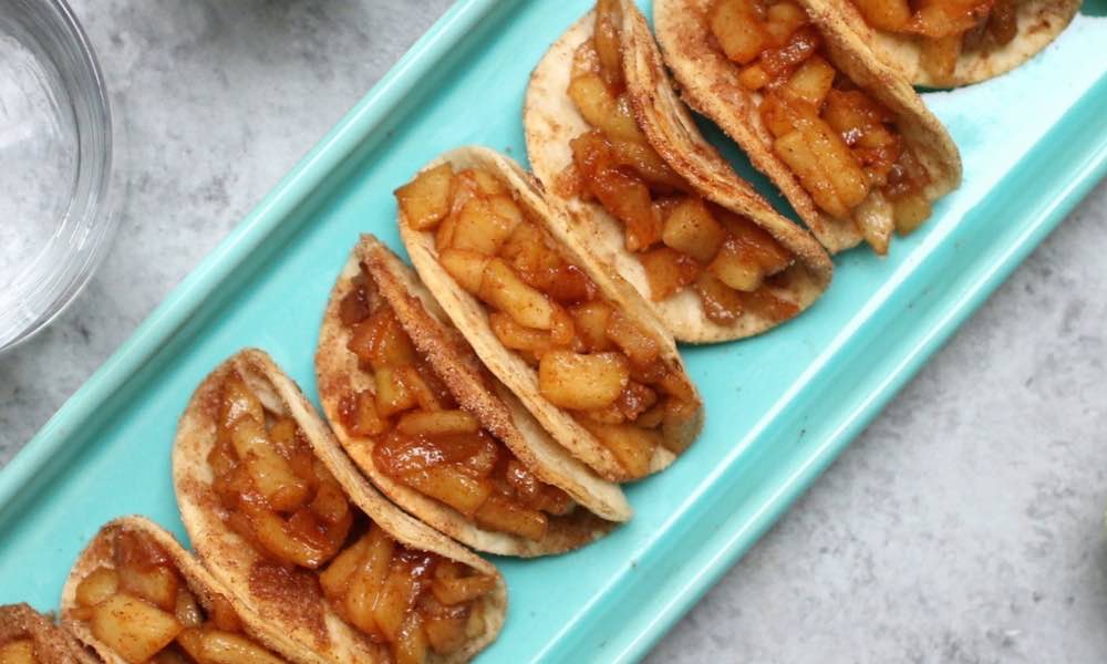 Super Easy Baked Apple Pie Tacos – delicious cinnamon sugary apple filling in a crispy and sweet taco, drizzled with caramel sauce, and then topped with whipped cream! The easiest dessert that comes together in no time. All you need is a few simple ingredients: Flour Tortillas, butter, cinnamon, sugar, apples, lemon, caramel sauce and whipped cream. It’s the perfect way to serve apple pie to a crowd! Quick and easy recipe. Great for party dessert and holiday brunch such as Easter, Mother’s Day or Father’s Day. Video recipe. | Tipbuzz.com