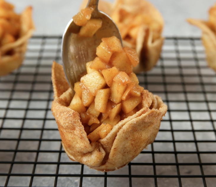 Spooning the apple pie filling into the tortilla cups