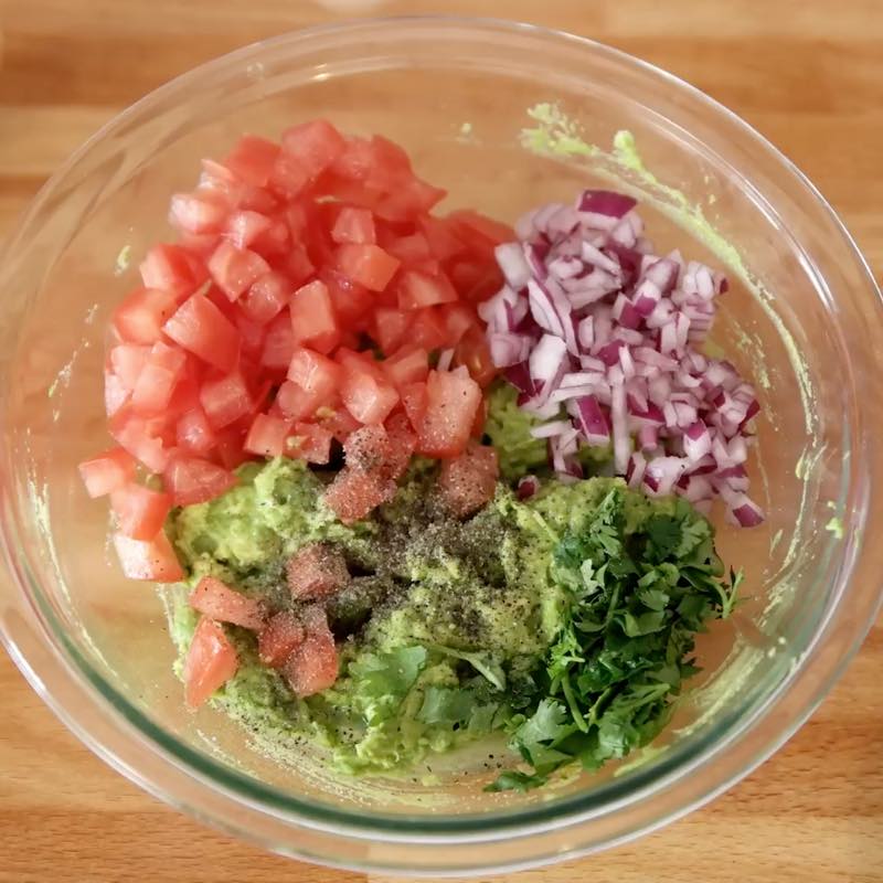 Ingredients for the filling in a mixing bowl: avocados, tomato, red onion, cilantro and lime juice