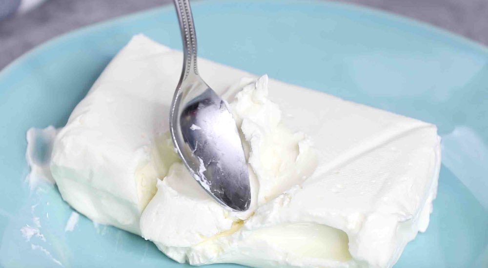 Using the back of a spoon to check whether the cream cheese is softened