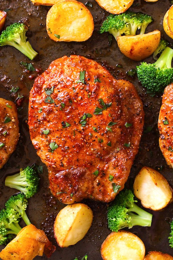 Oven baked boneless pork chops on a sheet pan with potatoes and broccoli. A simple dry rub seasoning produces a caramelized crust while adding flavor and ensuring tender and juicy pork chops.