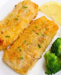 Baked breaded haddock fillets garnished with fresh lemon and served with a side of broccoli