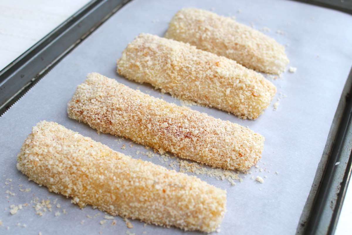 Breaded fish fillets on a sheet pan ready for baking