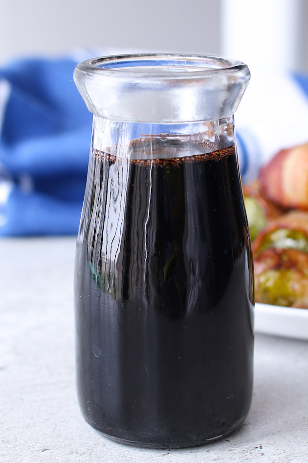 Balsamic reduction or balsamic glaze stored in a small glass jar for future use. 