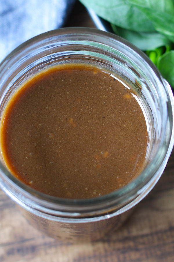 Closeup photo of a freshly made balsamic vinaigrette recipe in a mason jar showing the oil vinegar emulsion that produces this dressing's characteristic flavor 