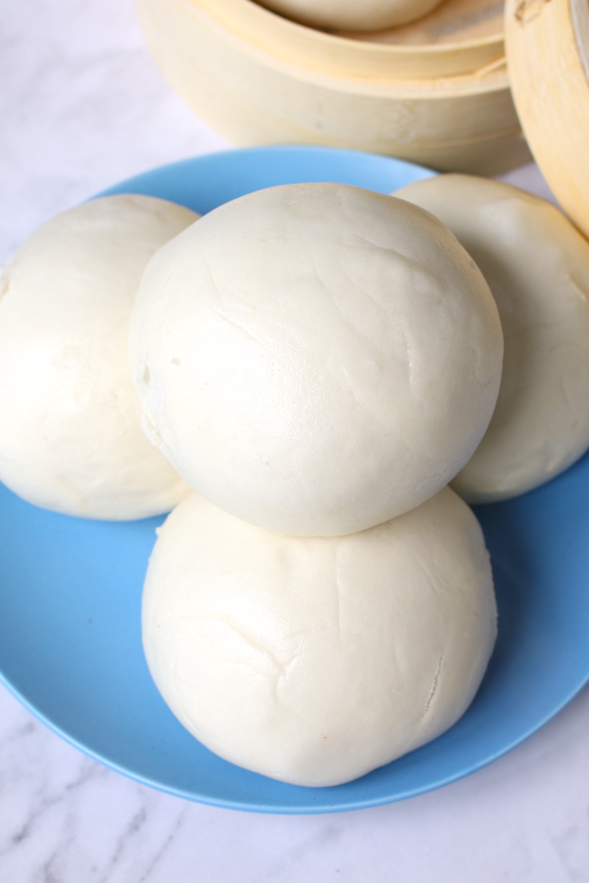 Overhead view of round bao buns stacked on a serving plate