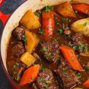 Homemade Beef Stew with carrots and potatoes cooked in a Dutch oven with fresh parsley on top