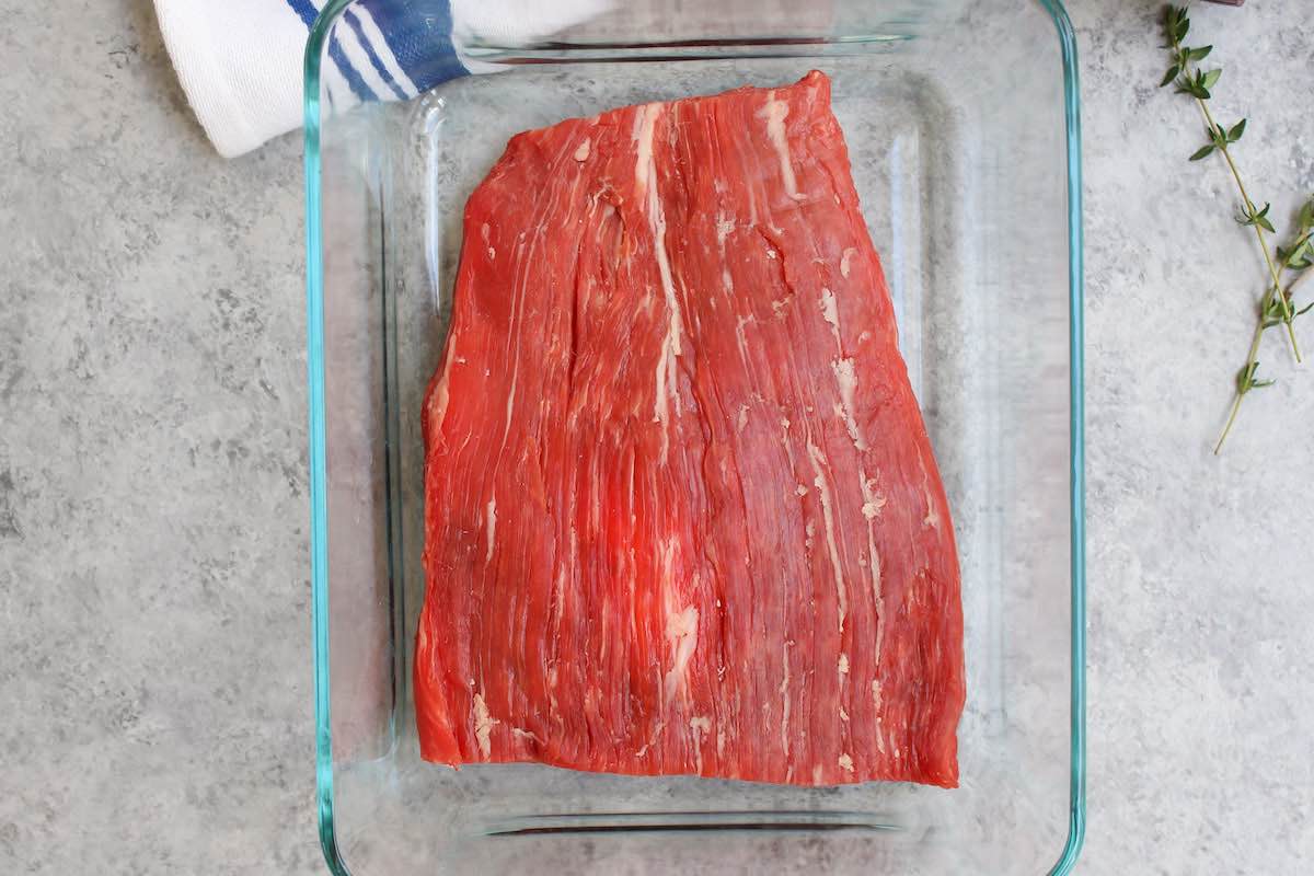 Place raw flank steak in a large container.