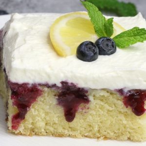 Blueberry Lemon Poke Cake – bursting with irresistible lemon and blueberry flavor. The lemon cake is poked with holes, and drizzled with lemony and sweet blueberry sauce, then topped with whipped cream. So Good! Perfect for a holiday party! Easy recipe. Vegetarian. Video Recipe | Tipbuzz.com