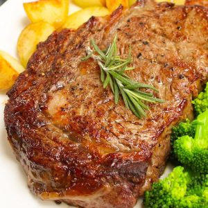 Perfectly broiled steak served with potatoes and broccoli on a serving plate with a sprig of rosemary for garnish.