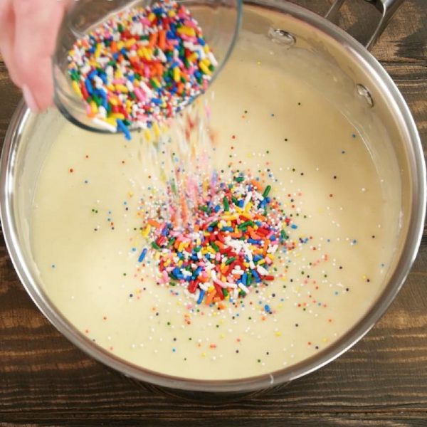 Cake Batter Fudge - this photo shows adding colorful sprinkles to cake bater fudge batter during preparation in a saucepan
