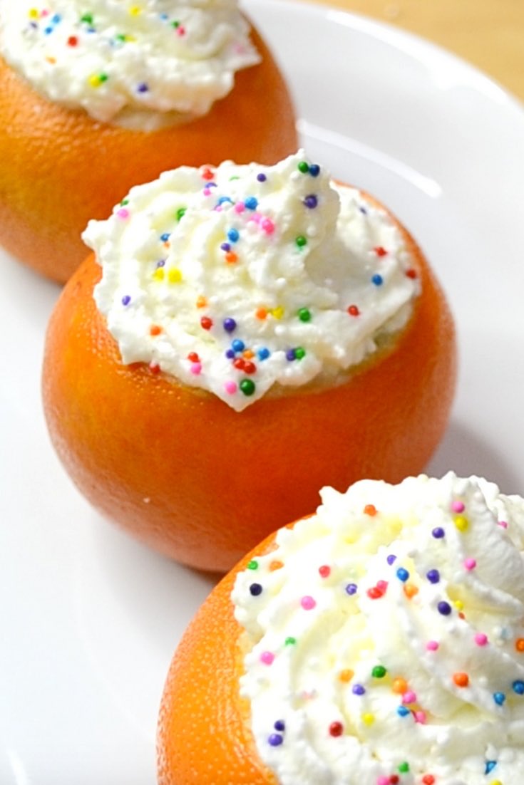 Campfire cakes in a orange shells with whipped cream on top