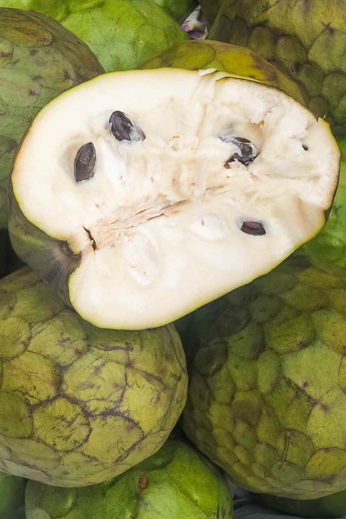 Closeup of the cherimoya including a freshly cut cross-section showing the seeds