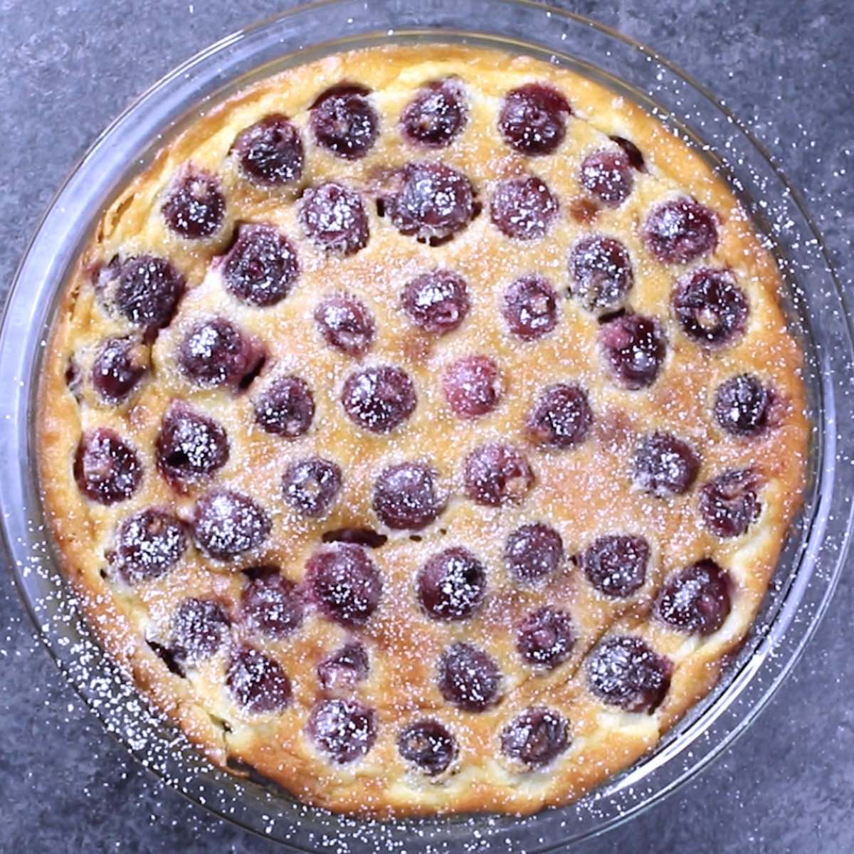 Overhead view of a freshly baked cherry clafoutis dusted with powdered sugar