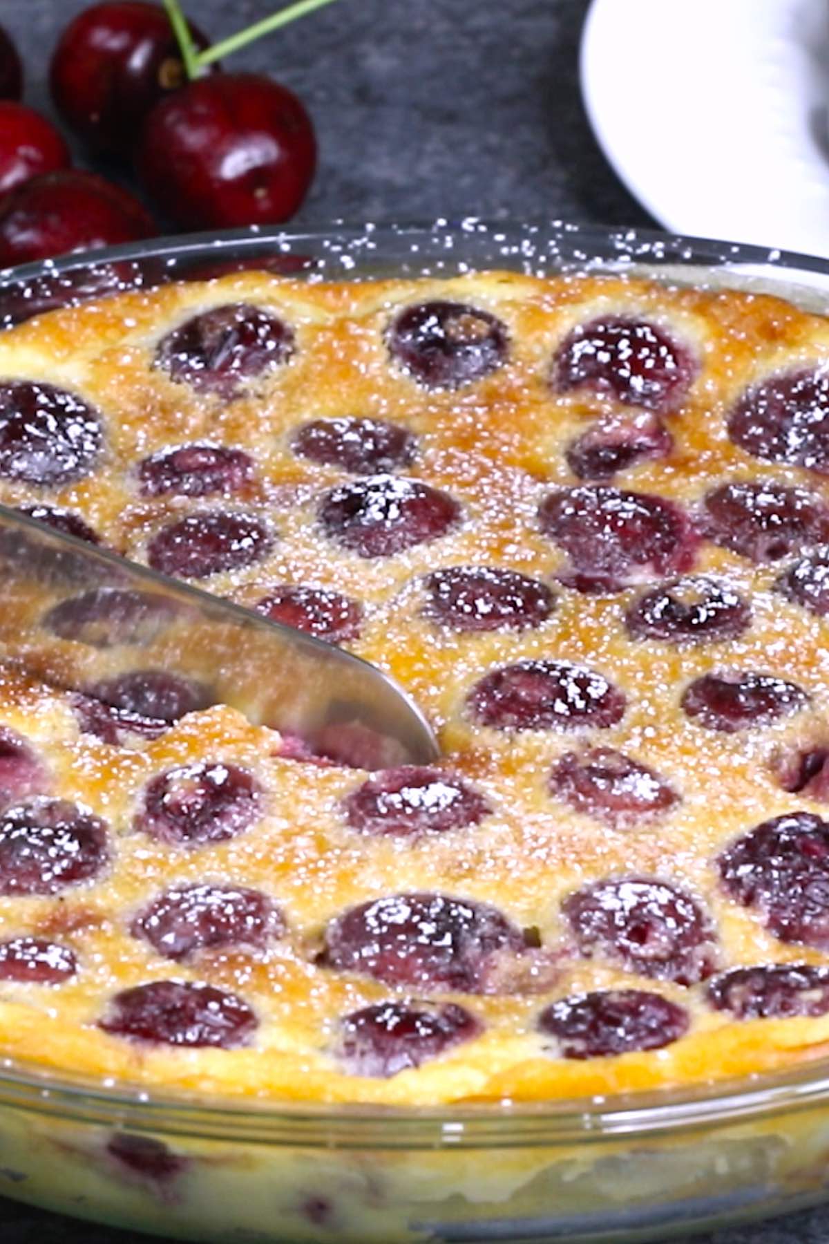 Side view of a cherry clafoutis being cut into wedges