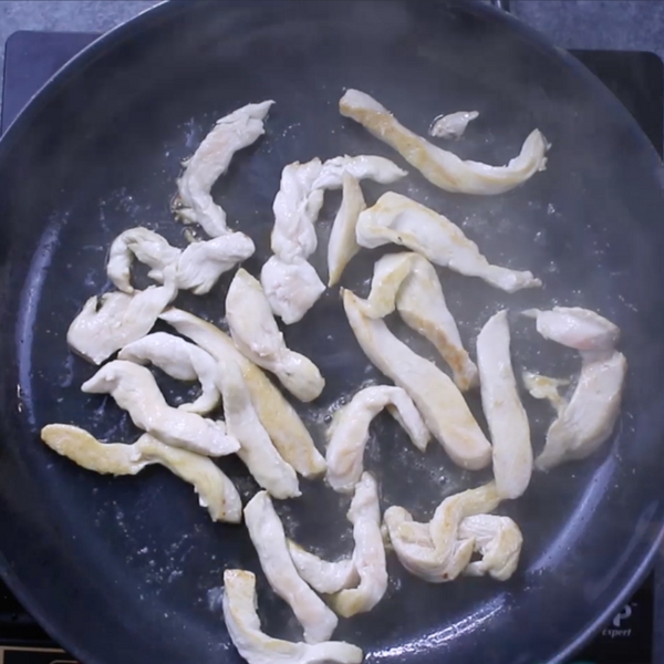 Sauteeing strips of chicken in a skillet