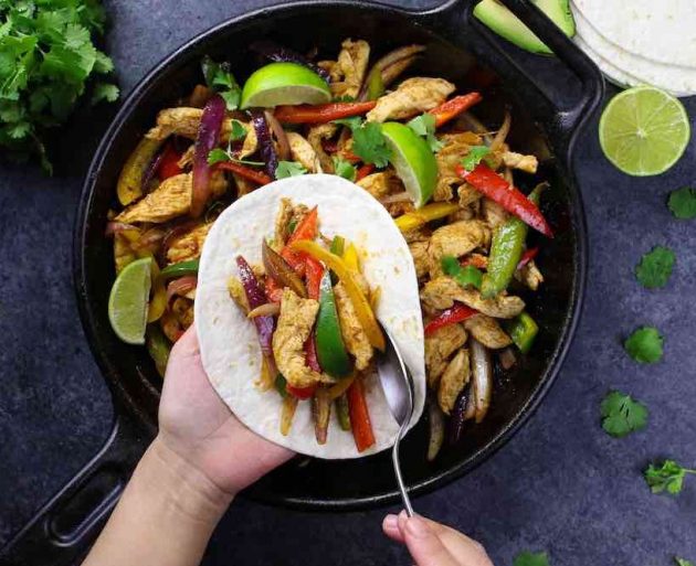 Assembling chicken fajitas on a tortilla