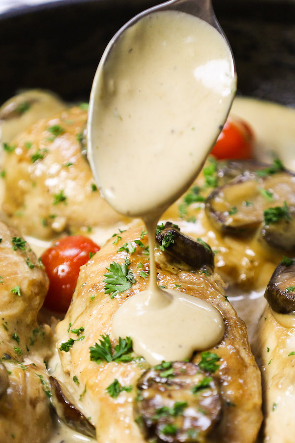 Creamy Chicken Marsala - this is a closeup view of spooning creamy marsala onto cooked chicken in the pan after cooking