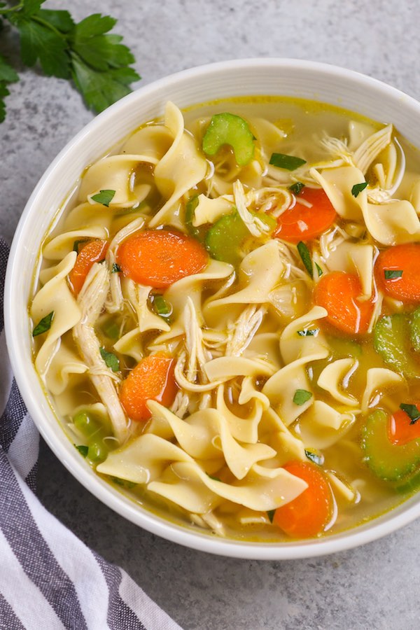 A white bowl filled with chicken and noodle soup