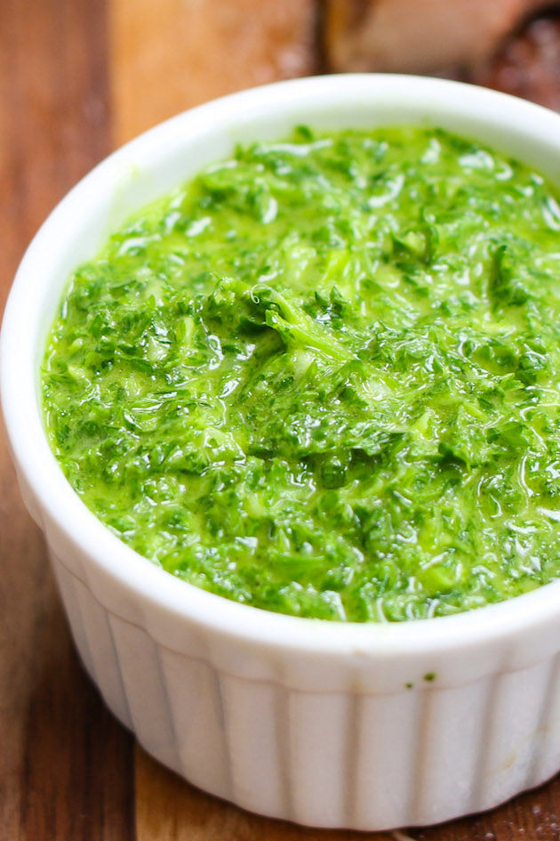 Chimichurri sauce made with finely chopped parsley, olive oil, oregano, minced garlic and vinegar. Served in a white container.