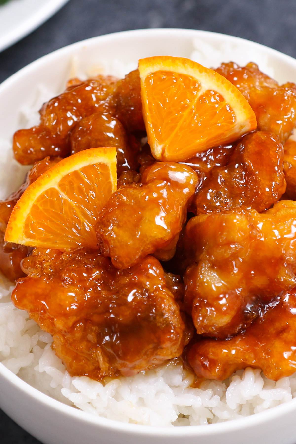 Sticky Orange Chicken garnished with fresh orange wedges and served on a bed of steamed rice