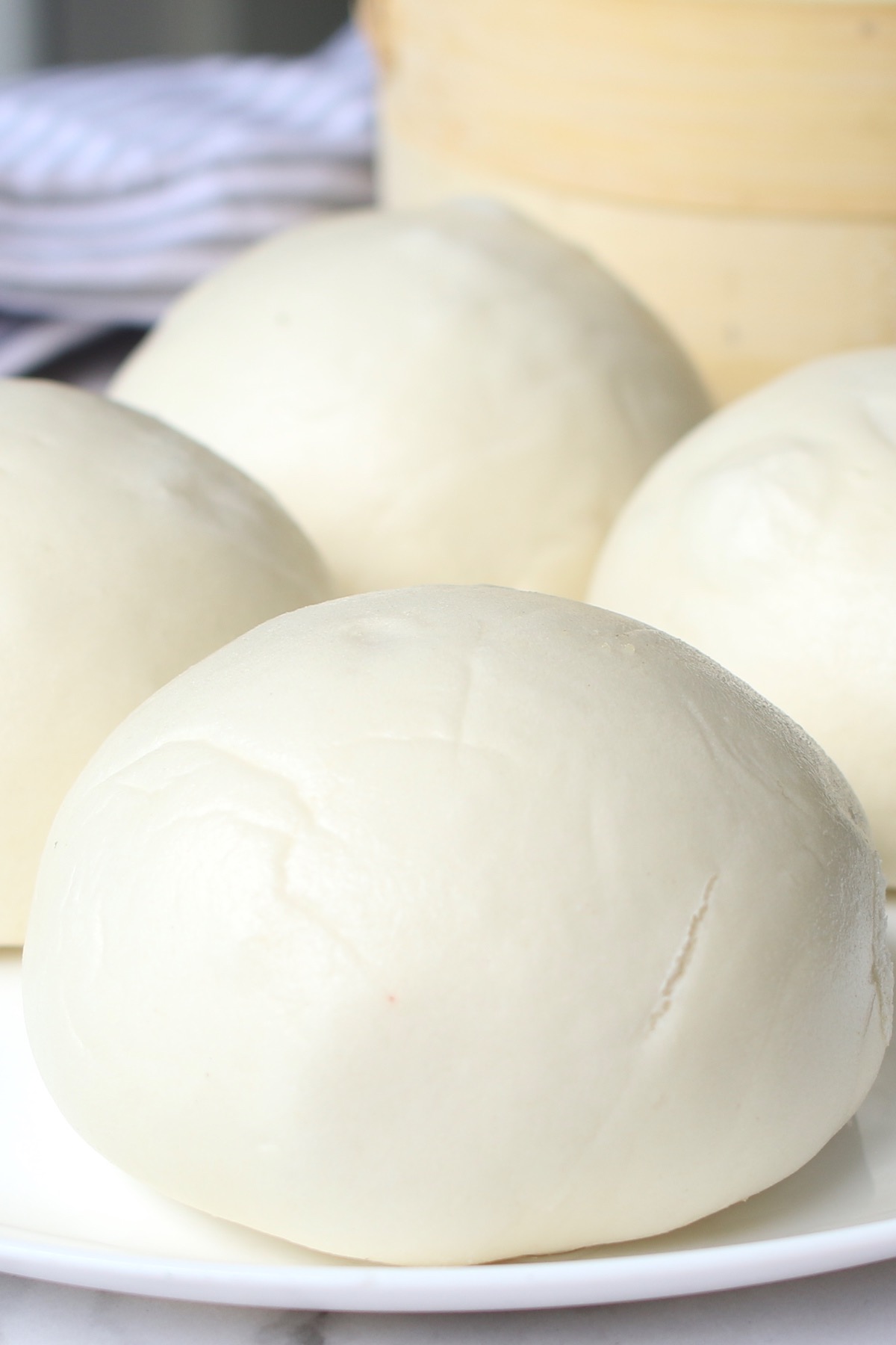 Closeup of Chinese Steamed Buns on a serving plate showing the silky smooth texture of the dough 