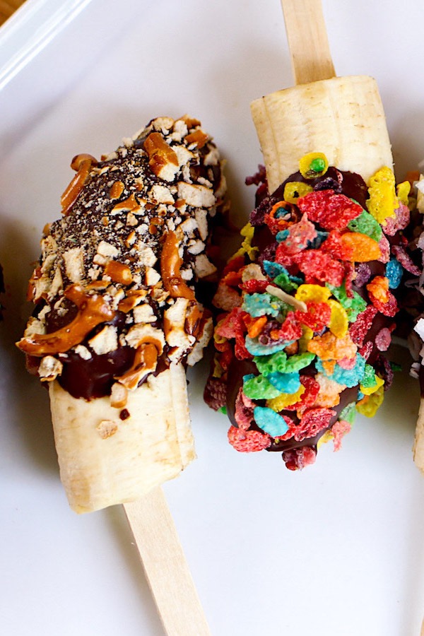 Chocolate Covered Bananas are the easiest snacks ever! Just 3 ingredients: banana, chocolate and coconut oil, plus whatever toppings you like such as crushed M&Ms, fruity pebble cereal, cinnamon toast crunch and colored sprinkles. Beautiful and irresistibly delicious! Quick and easy recipe. Kids friendly. Video recipe. | Tipbuzz.com #ChocolateCoveredBananas #ChocolateBananas