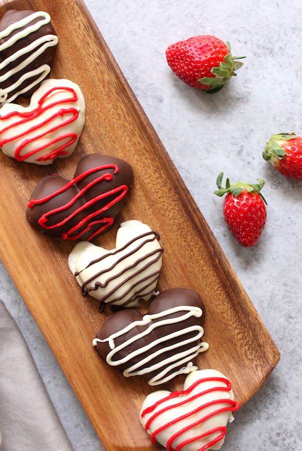 Chocolate Covered Strawberry Heart – The easiest and most beautiful homemade gifts around! It takes 30 minutes to make and taste absolutely heavenly. Fresh and juicy strawberries are cut in half, making the heart shapes, then covered with gourmet semisweet or white chocolate. Decorate them with red decorating gel and melted chocolate. Just 4 ingredients are all you need! So good! Quick and easy recipe, no bake dessert, valentine’s recipe, mother’s day recipe. Video recipe. | Tipbuzz.com