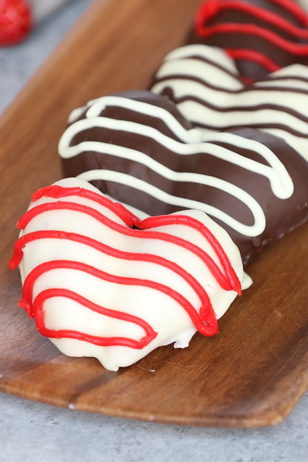 This photo is a closeup of heart shaped Chocolate Covered Strawberries with drizzle on a serving plate