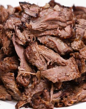 A mound of tender pulled chuck roast on a serving plate