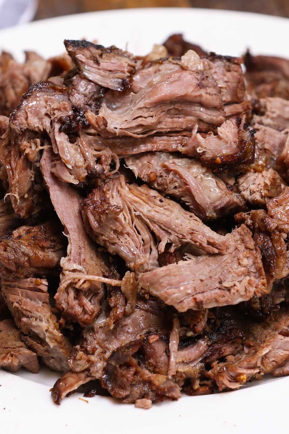 A mound of tender pulled chuck roast on a serving plate