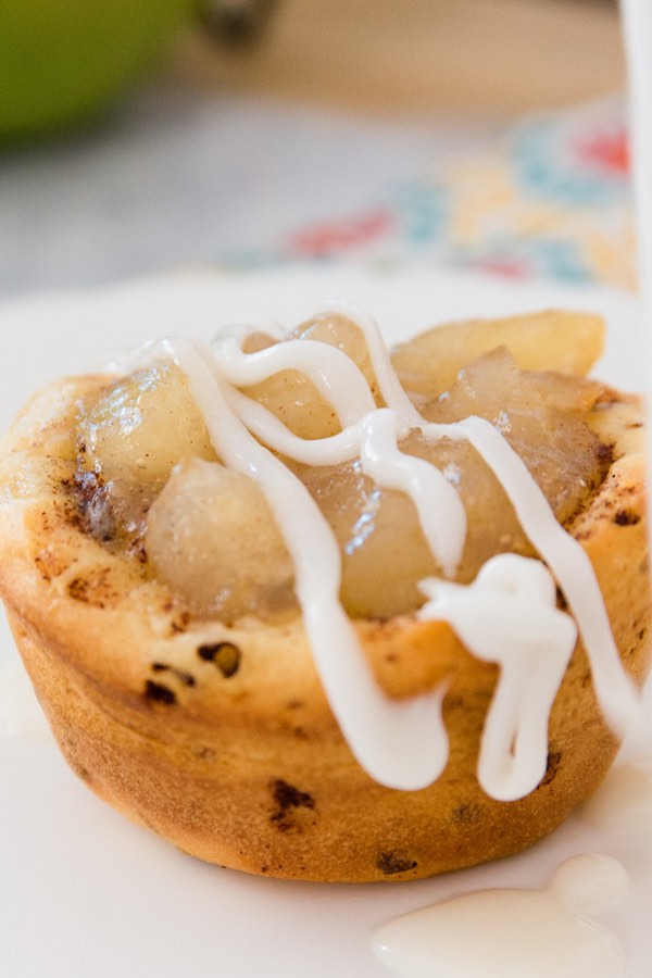 Closeup of a cinnamon roll apple pie cup with icing drizzled on top