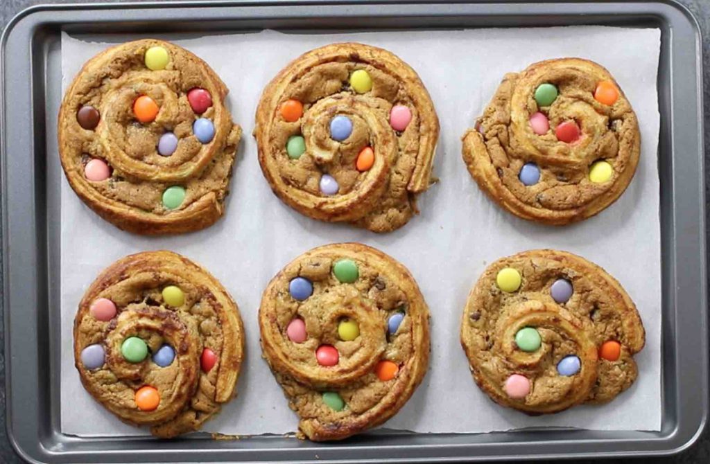 This photo shows cinnamon roll cookies that have turned golden brown after baking for 10 minutes on a cookie sheet in a 350F oven.