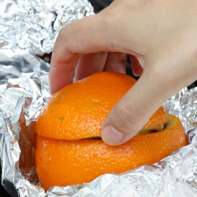 Removing the foil from a campfire cinnamon roll to reveal the orange shell