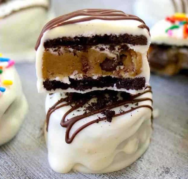 Closeup cross-section of cookie dough stuffed oreos showing the layers of cookie sandwich, edible cookie dough and chocolate coating