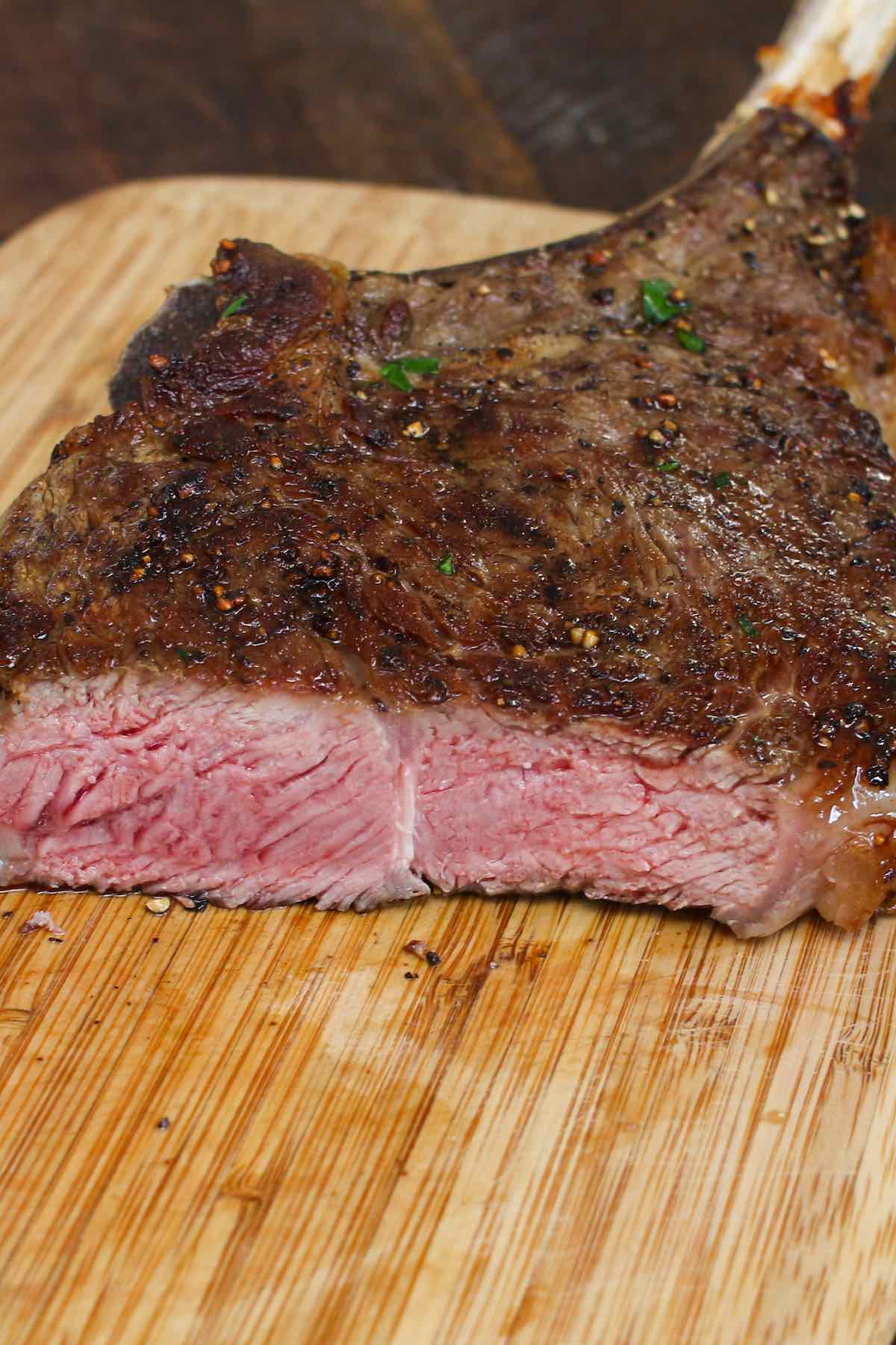A cowboy ribeye cooked medium showing a pale pink interior