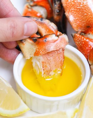 Jonah crab claws being dipped in melted butter