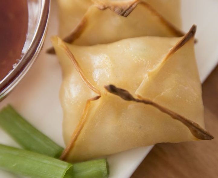 Cream cheese wontons on a serving plate with dipping sauce
