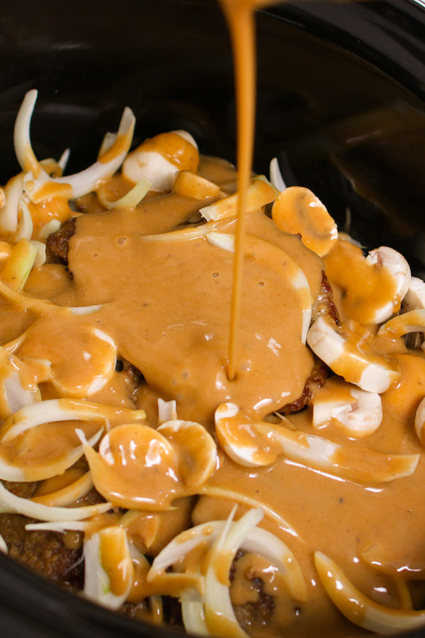 Pour the mixture of cream of mushroom, onion soup, beef stock, thyme, onion and mushroom over the steak in the slow cooker