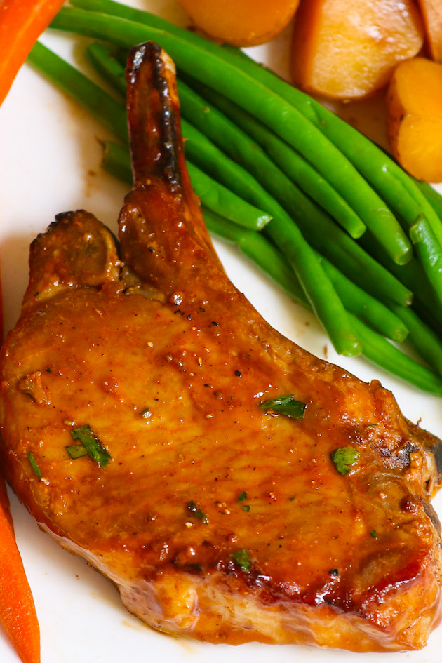 Crock Pot Pork Chops with potatoes in a delicious gravy on a serving plate with vegetables