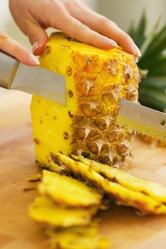  Eine Ananas mit einem Messer schneiden