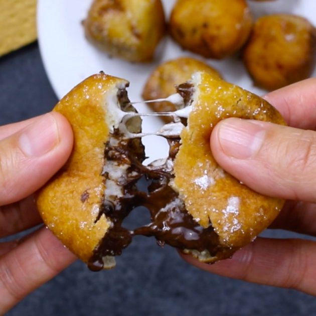 Deep fried smores - this photo is a closeup of pulling apart a deep fried s'more with melted chocolate and marshmallow oozing out of the inside