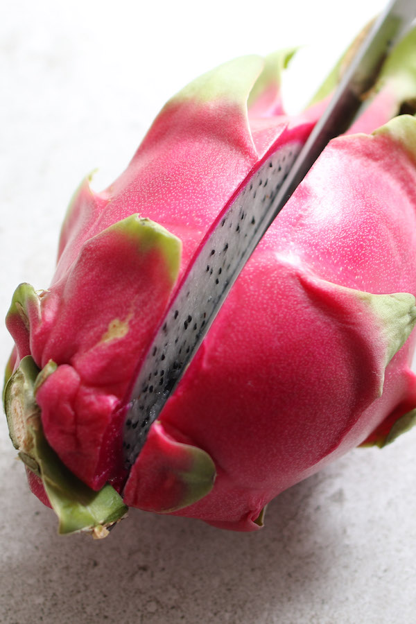 This photo shows cutting a dragon fruit in half with a chef's knife