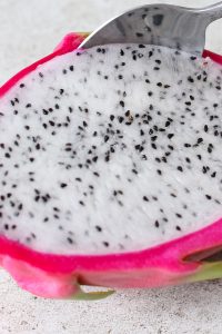 This photo show how to peel dragon fruit by sliding a spoon between the skin and the flesh