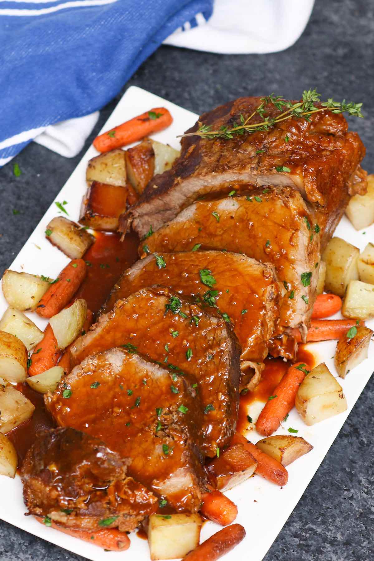 Sliced eye of round roast on a platter with carrots and potatoes