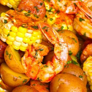 Shrimp Foil Packets being served after grilling: juicy jumbo shrimp, baby potatoes, corn and sausage with Cajun seasoning, lemon juice and fresh parsley for a delicious meal.