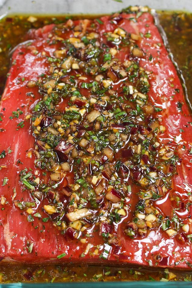 A piece of flank steak in a homemade marinade with soy sauce, olive oil, red wine vinegar, garlic and other ingredients