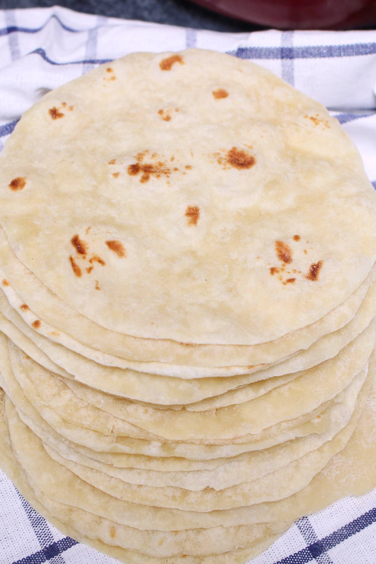 Homemade flour tortillas piled up on a towel