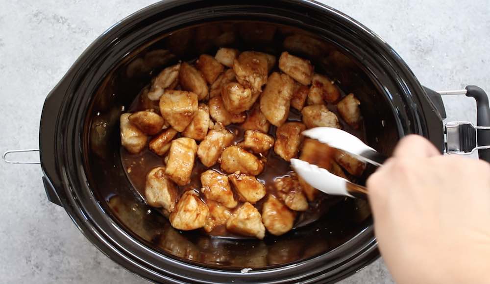 Slow Cooker General Tso's Chicken - this photo show tossing the chicken pieces with the sauce to coat before turning on the crock pot